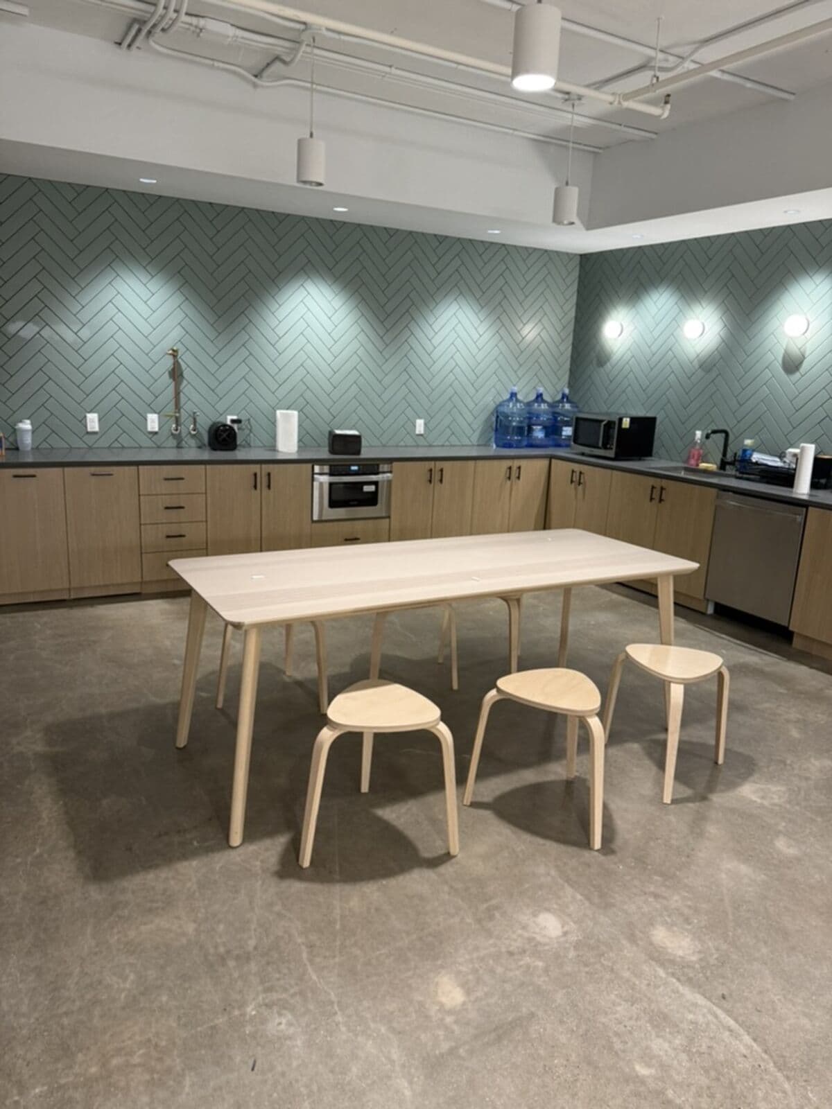 The kitchen on move-in day: bare counters and a small table with stools on unfinished concrete